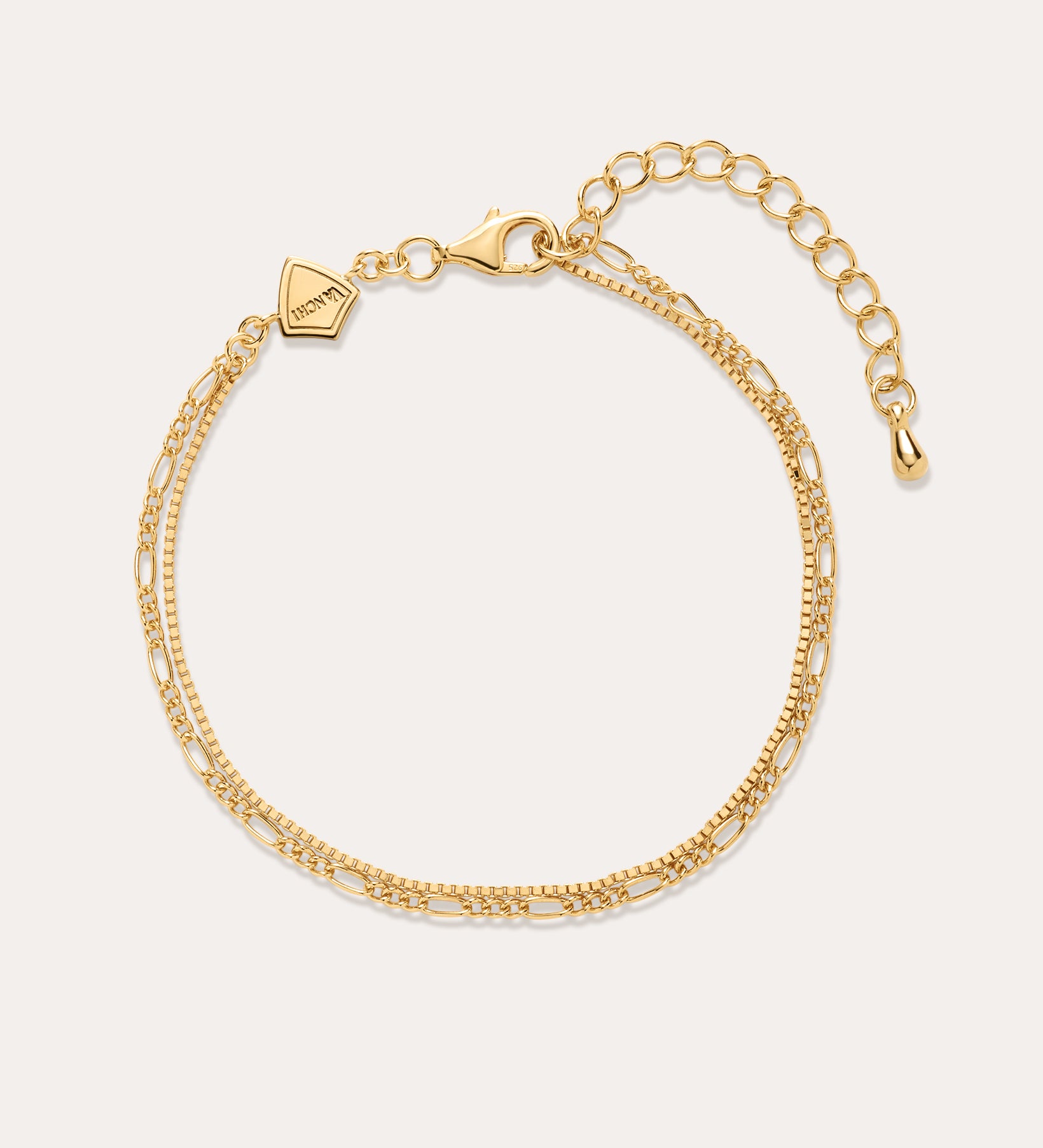 The Figaro And Box Chain Layered Bracelet in 18k Gold Plated features two intertwined strands in a mini Figaro box chain design with a lobster clasp, adjustable extender, and geometric tag, shown on a plain off-white background.