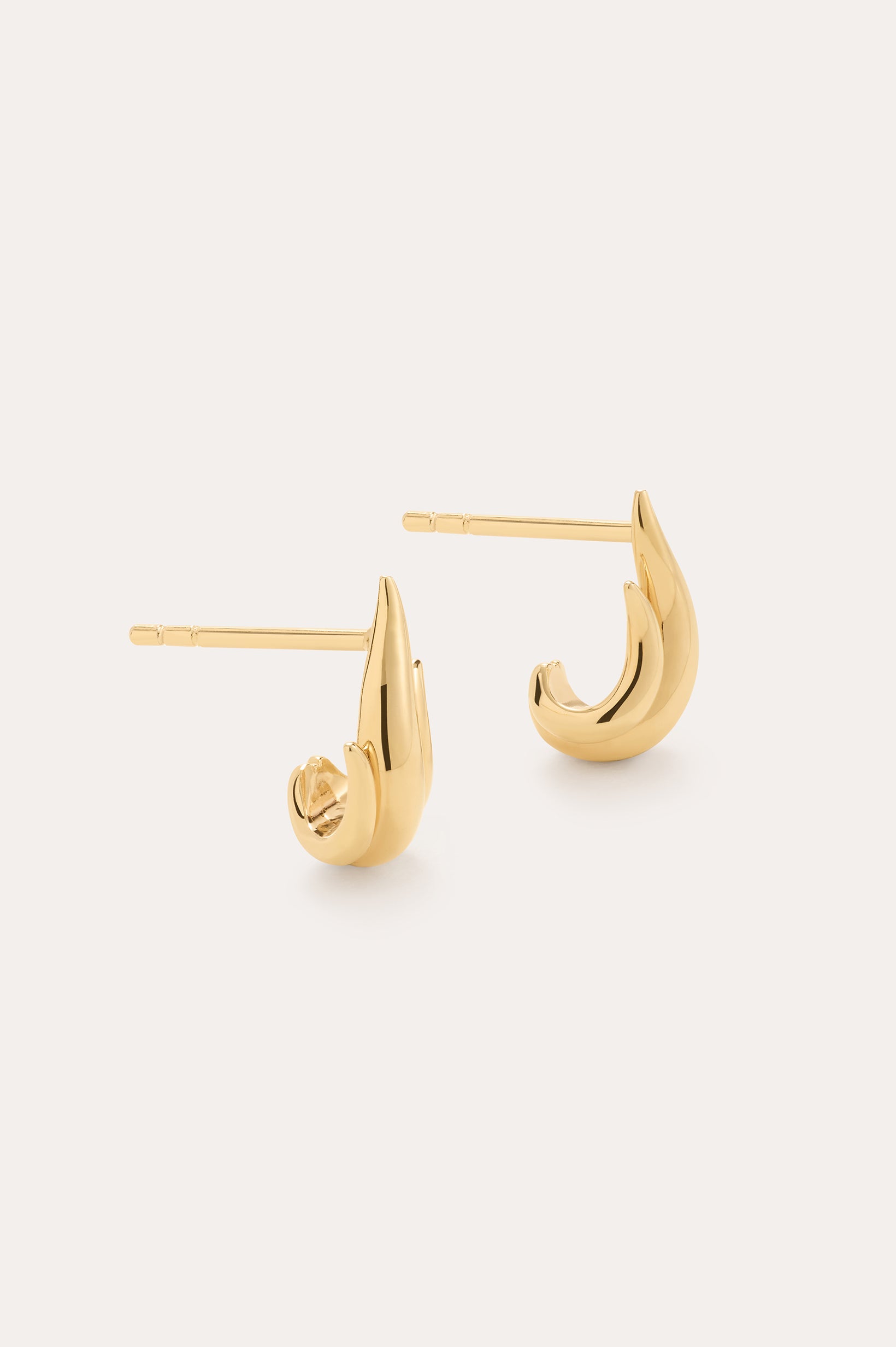 The Flame Stud Earrings in Gold are a shiny, 18k gold plated, crescent-shaped pair shown on a plain light background—one lying flat and the other upright to highlight their sculptural design and post backs.