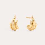 The Flame Stud Earrings in Gold, crafted with 18k gold plating and shaped like abstract flames, are shown against a neutral background—one earring displays the front view, while the other reveals the sculptural side and post.