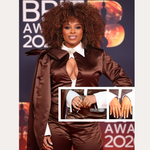 Fleur East poses on the red carpet in a brown satin outfit with dramatic sleeves and a white collar, accessorized with the Nola Pavé Triple Band Ring in Silver, a brown clutch bag, and manicured nails at the 2023 BRIT Awards.