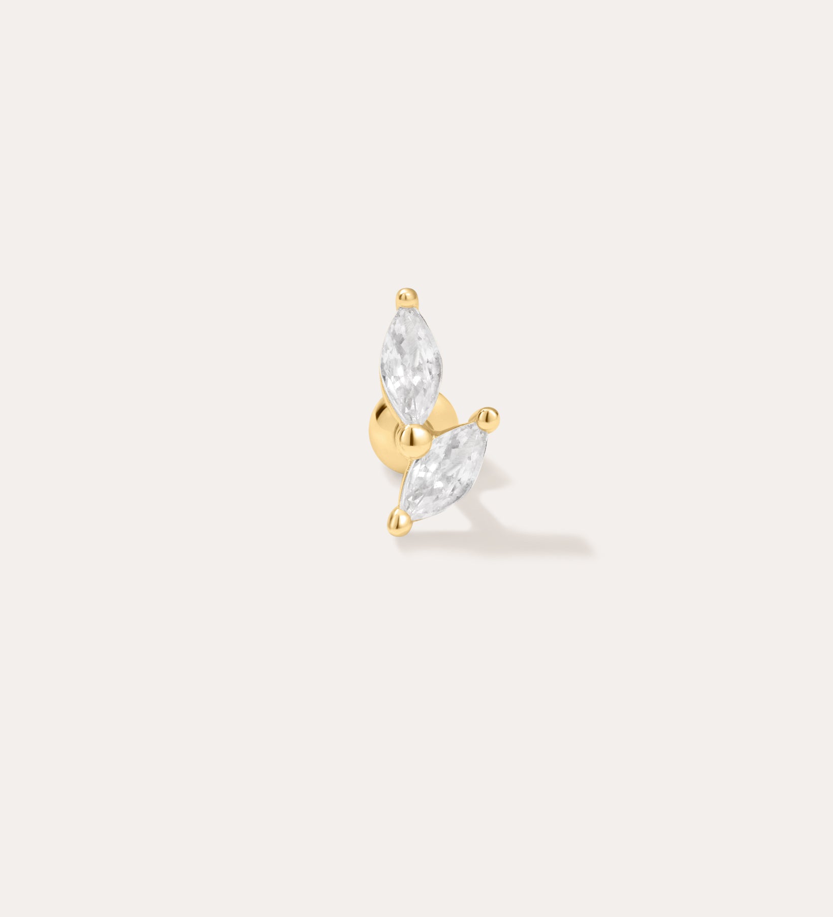 The Flora Barbell Stud in Gold showcases two marquise-cut clear gemstones set in a V shape, ideal as cubic zirconia earrings or for helix piercings, displayed against a plain off-white background.
