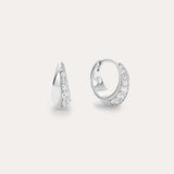The Georgie Crystal Knife Edge Huggie Hoop Earrings in Silver feature a row of sparkling white stones, shown on a plain light background with one earring displayed from the front and the other from the side.