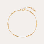 The Bamboo Chain Anklet in Gold features delicate cylindrical bar accents, crafted with 18k gold plating and an adjustable clasp with extension chain for the perfect fit.