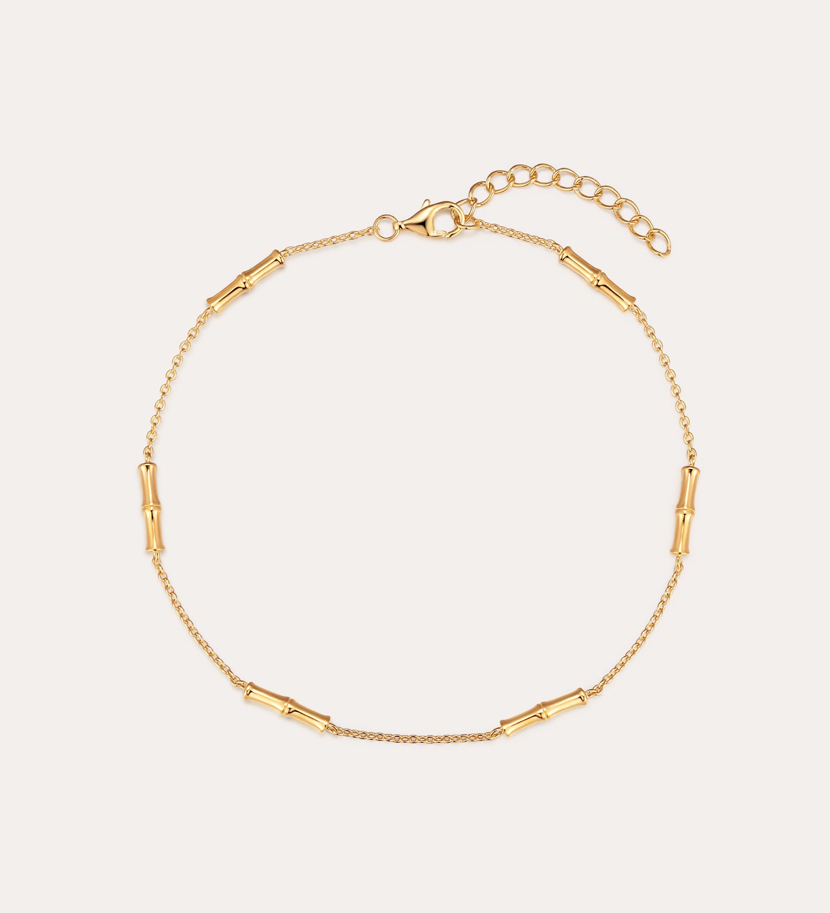 The Bamboo Chain Anklet in Gold features delicate cylindrical bar accents, crafted with 18k gold plating and an adjustable clasp with extension chain for the perfect fit.