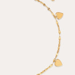 The Louise Gold Heart Anklet features four small gold hearts and a central heart with clear stones on a delicate gold chain. With an adjustable clasp, it can also be worn as a bracelet. Displayed on a plain light background.