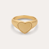 The Willa Heart Pinky Signet Ring in Gold is crafted in 18k gold with a flat heart-shaped centerpiece and a textured, rope-like border, shown against a plain light background.