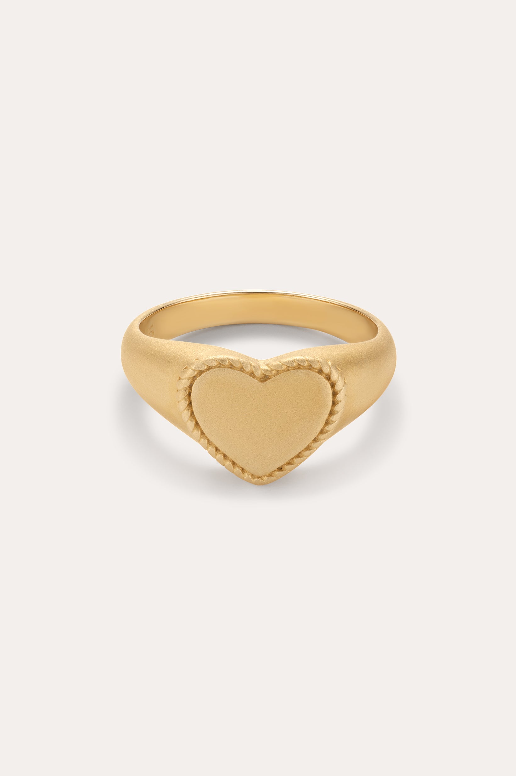 The Willa Heart Pinky Signet Ring in Gold is crafted in 18k gold with a flat heart-shaped centerpiece and a textured, rope-like border, shown against a plain light background.