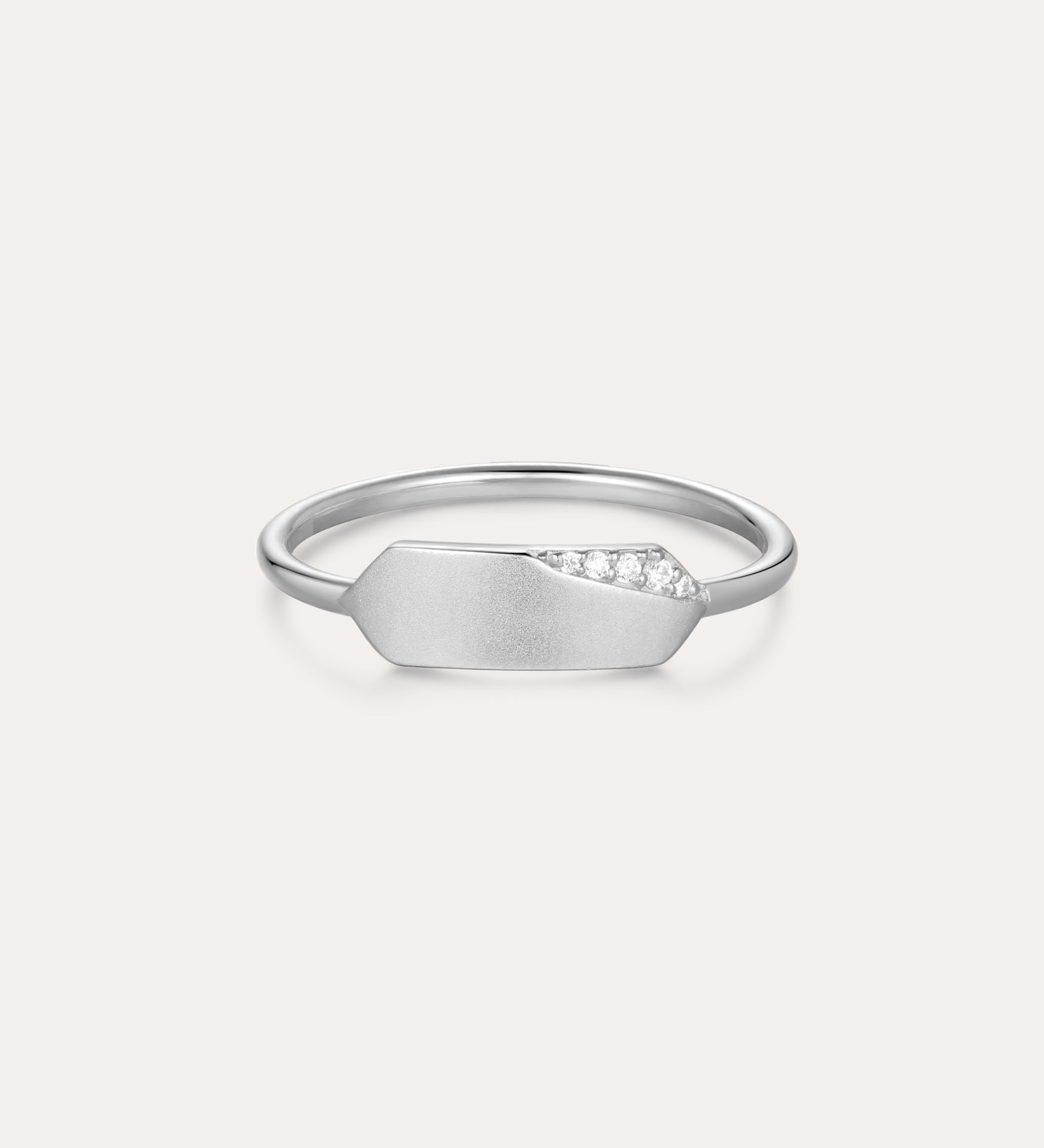 The Ines Horizontal Bar Ring in Silver features a delicate silver band with a flat geometric plate, accented by a sparkling cubic zirconia cluster on one side and finished in a subtle matte texture.