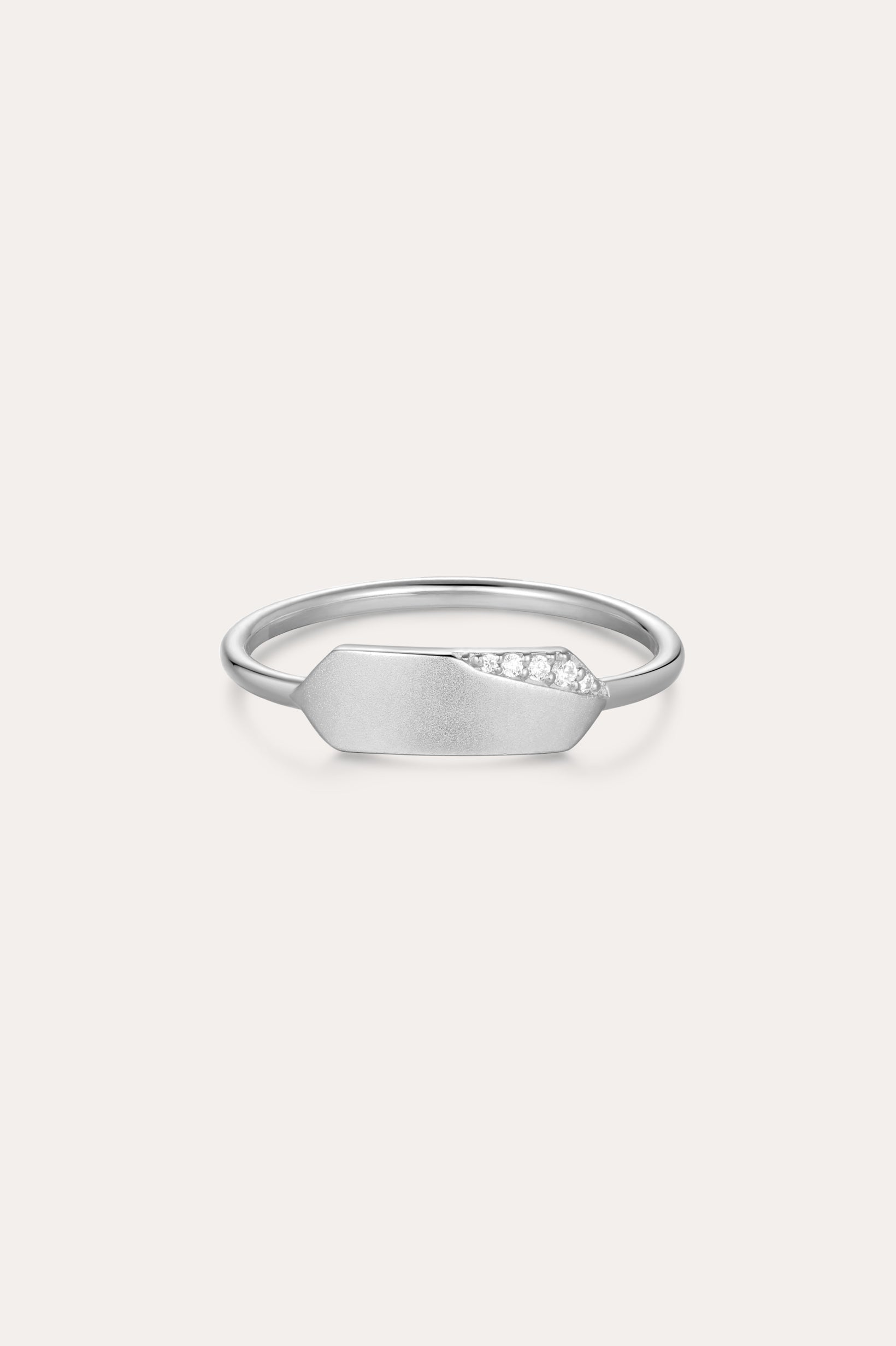 The Ines Horizontal Bar Ring in Silver features a delicate silver band with a flat geometric plate, accented by a sparkling cubic zirconia cluster on one side and finished in a subtle matte texture.