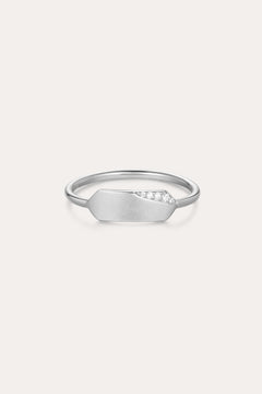 The Ines Horizontal Bar Ring in Silver features a delicate silver band with a flat geometric plate, accented by a sparkling cubic zirconia cluster on one side and finished in a subtle matte texture.