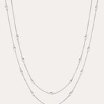 The Simona Double Chain Stacking Necklace in Silver features two delicate layers with small, evenly spaced beads along each chain, shown against a light background.