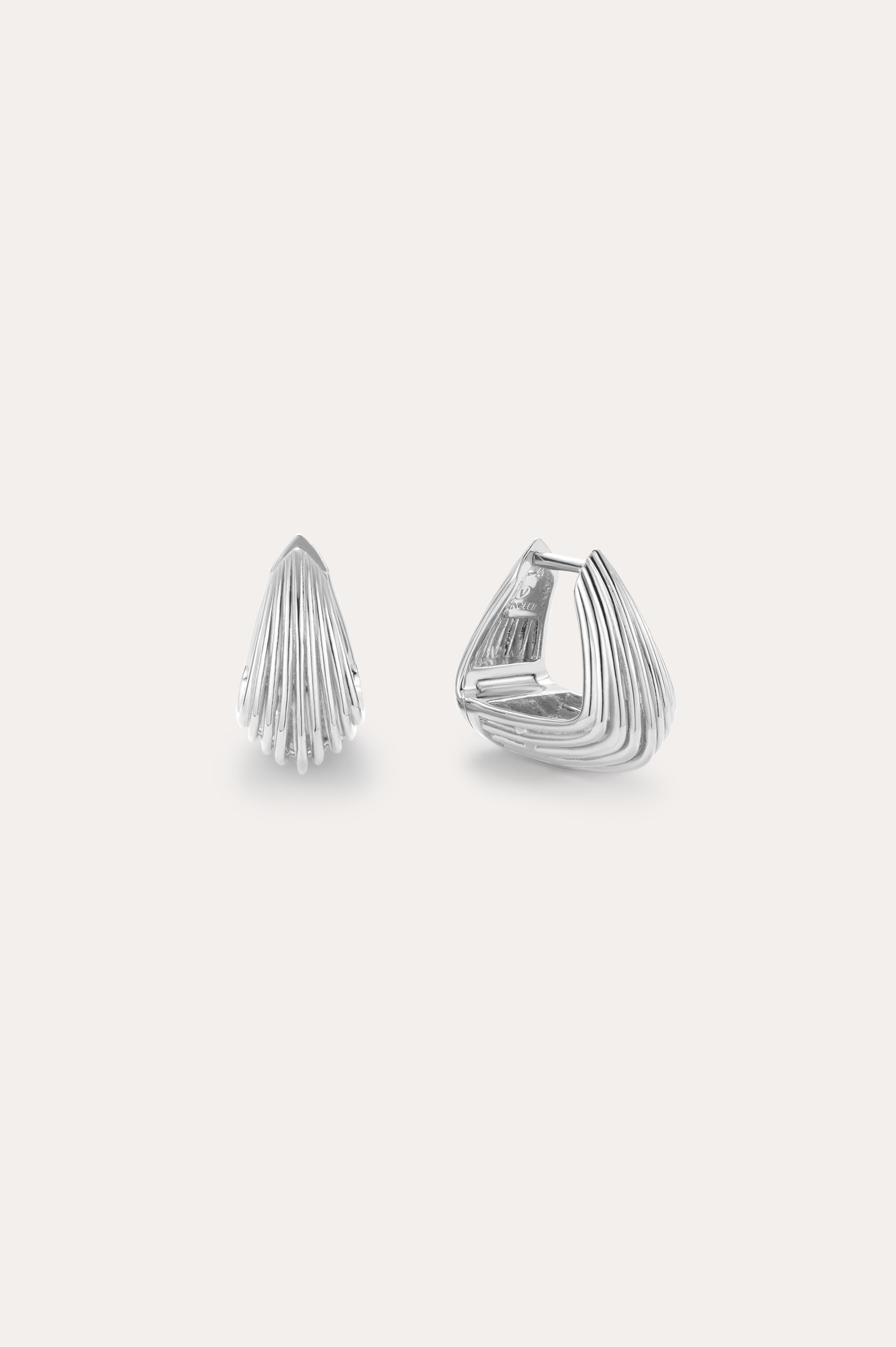 The Juno Ridged Chunky Hoops in Silver, featuring a modern fan-like ridged pattern, are showcased against a plain light background, with one earring closed and the other open to highlight the clasp design.