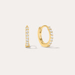 The Kiki Crystal Huggie Earrings in Gold feature a row of clear round crystals on 18k gold-plated hoops. One earring is shown from the side, the other from the front, against a light background—ideal for stacking.