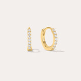 The Kiki Crystal Huggie Earrings in Gold feature a row of clear round crystals on 18k gold-plated hoops. One earring is shown from the side, the other from the front, against a light background—ideal for stacking.