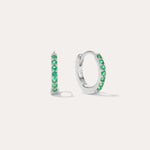 The Kiki Crystal Huggie Earrings in Sterling Silver/Green are displayed on a white background, with one earring facing forward and the other shown from the side.