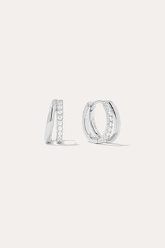 The Kira Crystal Double Hoop Huggies in Sterling Silver are shown, each featuring a row of sparkling round crystals along the front edge. The background is plain and light-colored.