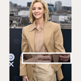 A woman with short blonde hair smiles outdoors in a city, wearing a beige blazer over a matching blouse and the Ayla Link Ring in Gold. Text above reads SPOTTED ON: and below, LISA KUDROW.