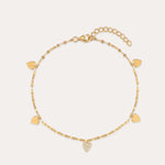The Louise Gold Heart Anklet features a delicate gold chain with small heart charms, including a central charm adorned with clear stones. It has an adjustable chain and lobster clasp closure.
