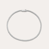 The Lumi Tennis Bracelet in Silver features a single row of sparkling cubic zirconia on a slim sterling silver band with a rectangular clasp, elegantly displayed against a plain, light background.