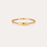 The Lya Horizontal Bar Stacking Ring in Gold features a sleek rectangular plate atop a twisted band, perfect for wearing solo or stacked with other rings. Shown against a simple light background.