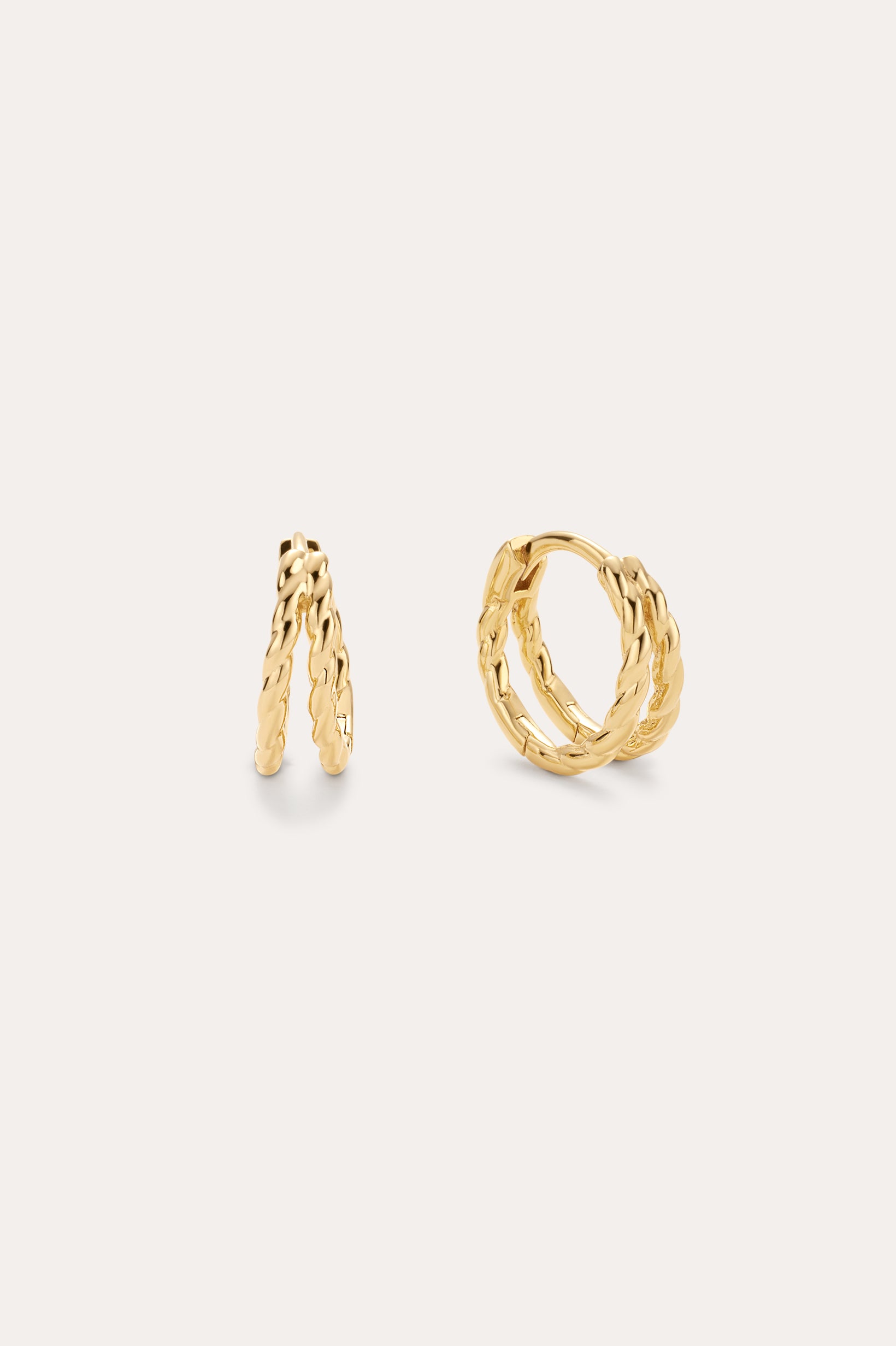 The Mae Twist Double Huggie Earrings in Gold, featuring a delicate twisted rope design, are displayed against a plain, light background.