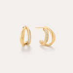 Nadine Pavé Twisted Stud Earrings in Gold feature a modern, sculptural design with a row of sparkling gemstones set along the inner edge and are displayed against a light neutral background.