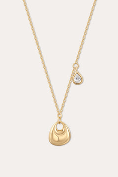 The Nora Double Pendant Necklace in Gold features a smooth sculptural pendant and a delicate teardrop charm with clear cubic zirconia, displayed on a plain light background.