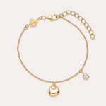 The Nora Double Pendant Bracelet in Gold features an adjustable clasp, a gold heart charm, and a teardrop-shaped cubic zirconia pendant for subtle sparkle.