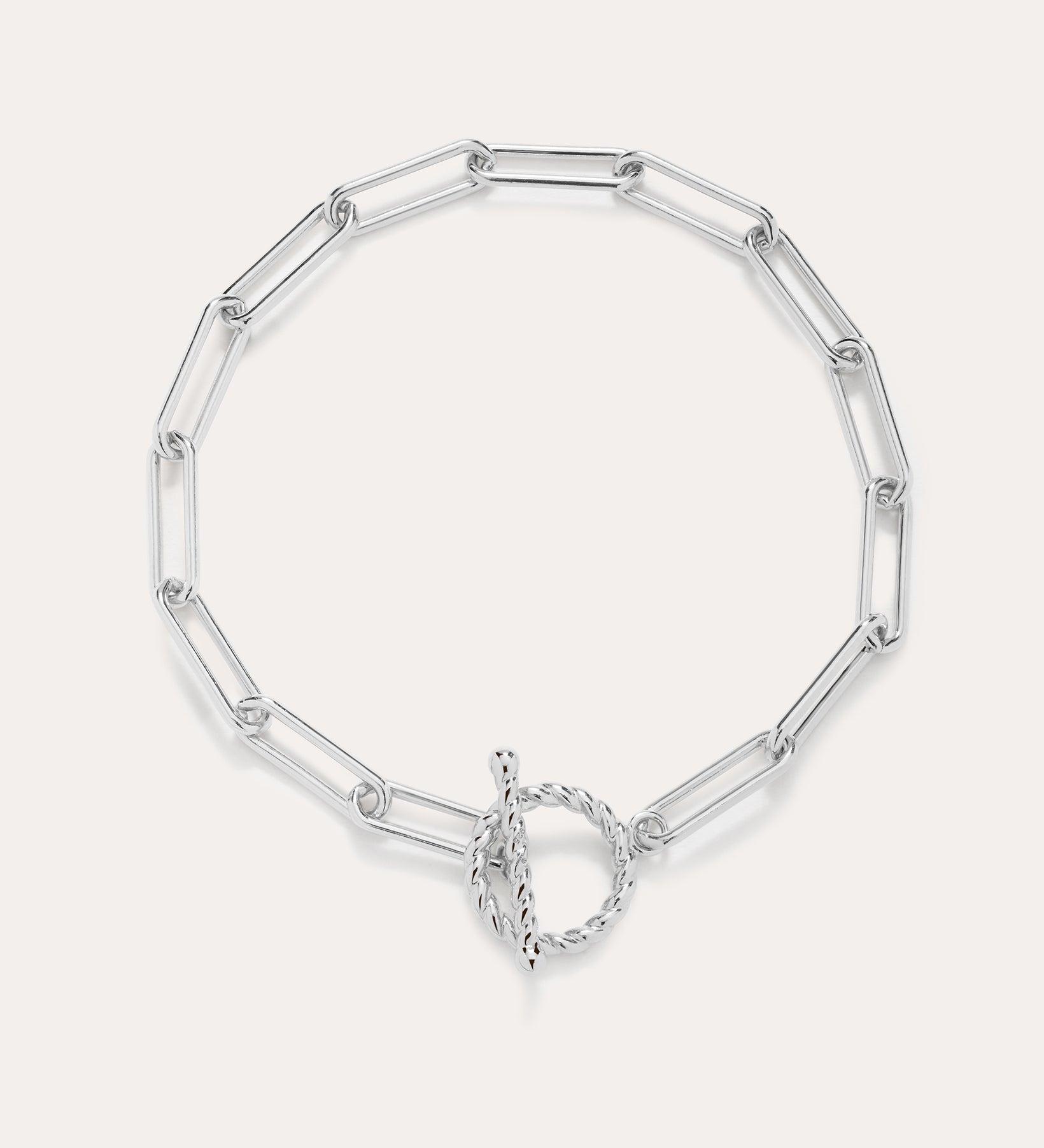 The Paperclip Toggle Bracelet in Silver features elongated oval links and a circular toggle clasp, displayed on a plain light background.