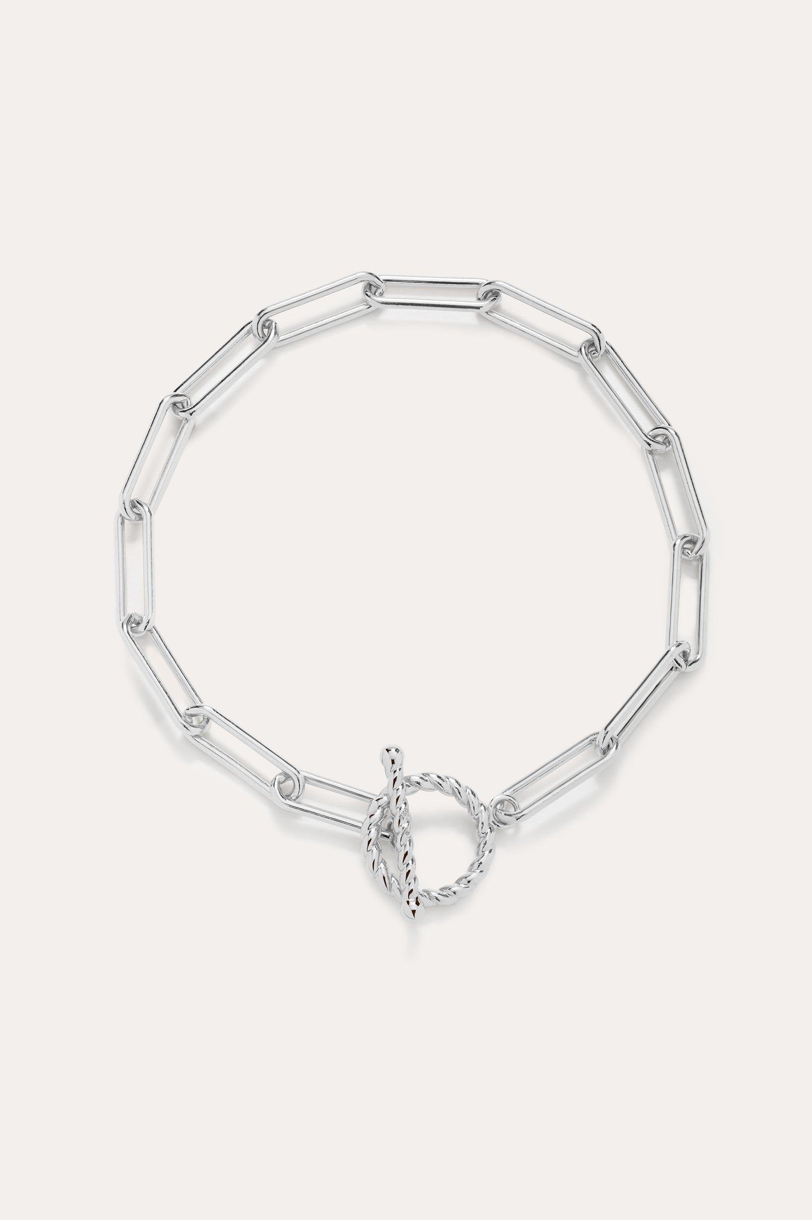 The Paperclip Toggle Bracelet in Silver features elongated oval links and a circular toggle clasp, displayed on a plain light background.