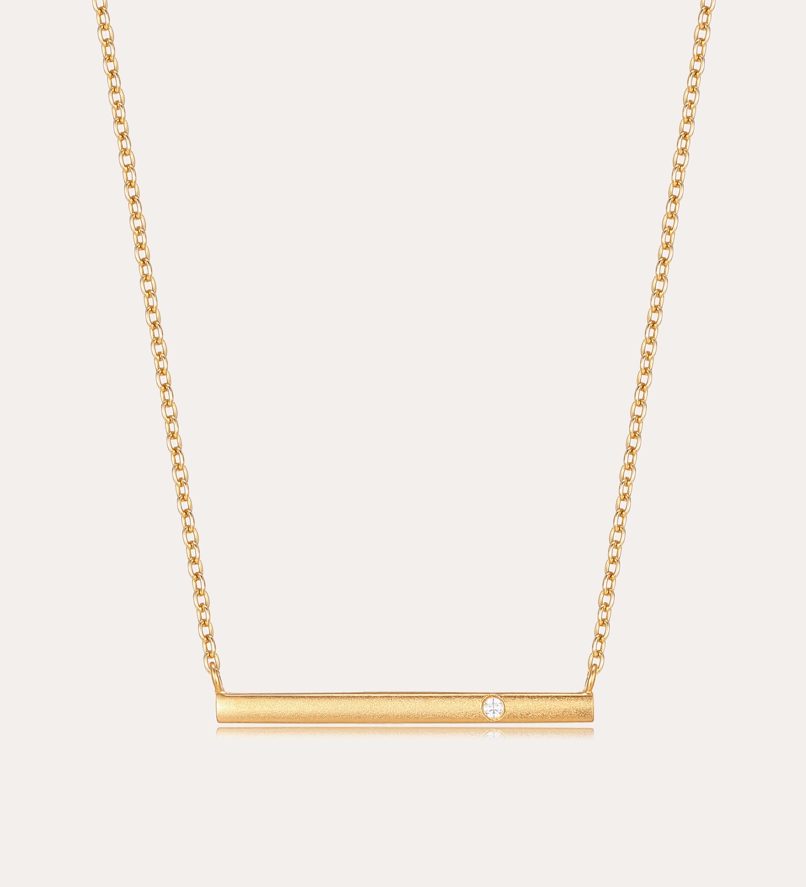 The Regina Horizontal Bar Pendant Necklace in Gold features a minimalist horizontal bar with an off-center cubic zirconia, making it perfect for lovers of simple, elegant jewelry.