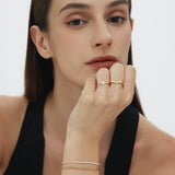 Woman wearing gold jewelry on a plain background