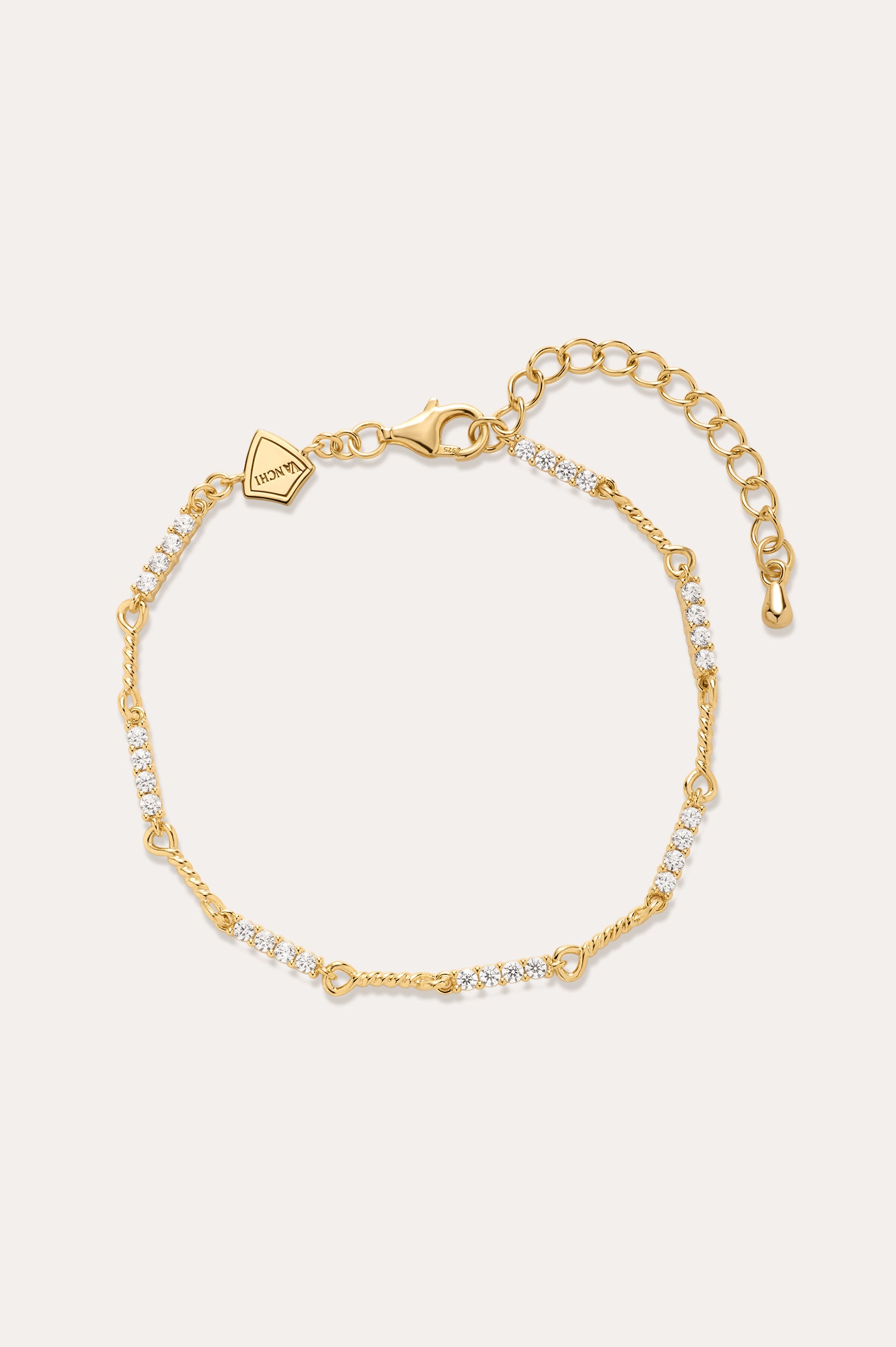 The Pia Crystal Link Bracelet in 18k Gold Plated features clusters of clear cubic zirconia, an adjustable extension chain, a lobster clasp, and a small hexagonal charm near the clasp for added elegance.