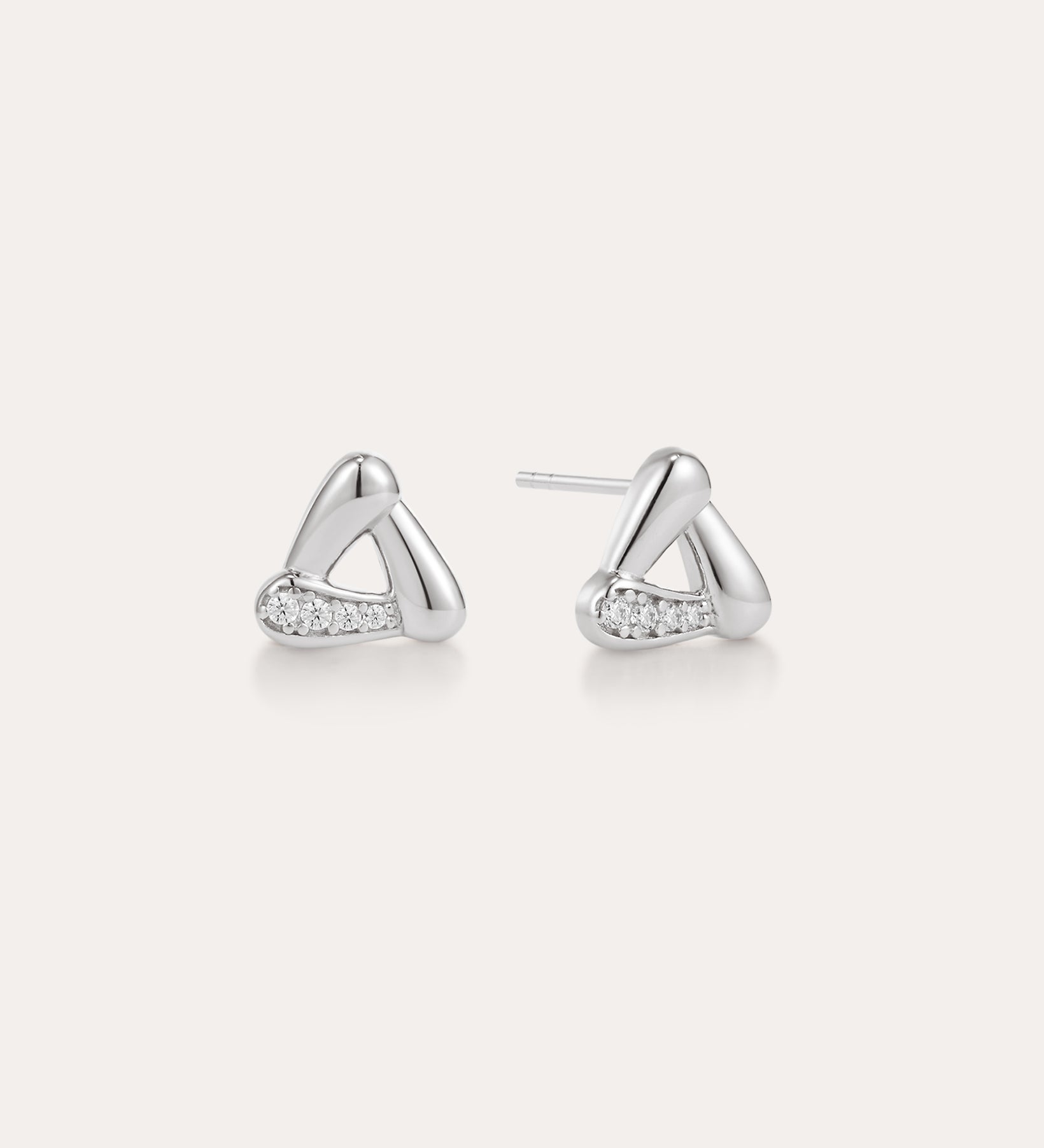 A pair of Colette Droop Link Studs in Silver, with smooth, rounded triangular shapes and small embedded cubic zirconia crystals on one side, displayed on a plain light background.