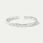 The Elodie Textured Torque Bangle in Silver is a minimalist, open-ended bracelet with a hammered finish, showcased on a plain white background.