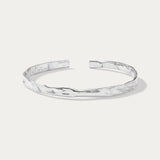 The Elodie Textured Torque Bangle in Silver is a minimalist, open-ended bracelet with a hammered finish, showcased on a plain white background.
