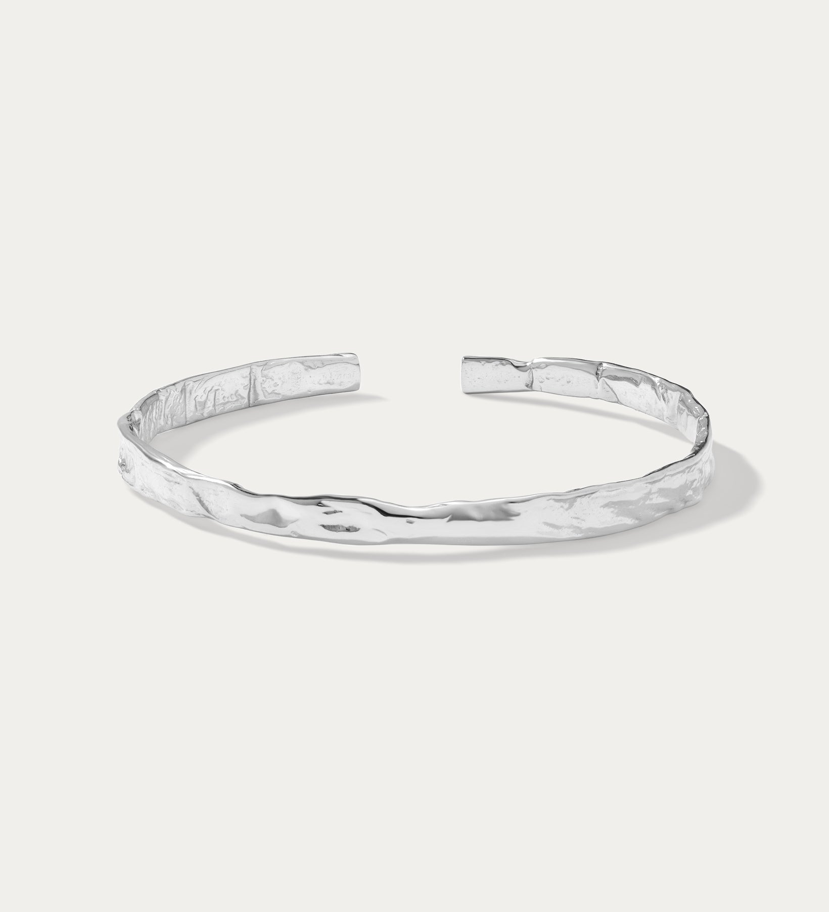 The Elodie Textured Torque Bangle in Silver is a minimalist, open-ended bracelet with a hammered finish, showcased on a plain white background.