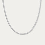 The Estelle Herringbone Chain Necklace in Silver is a sleek, minimalist chain shown against a plain white background.