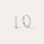 The Kiki Crystal Huggie Earrings in Sterling Silver feature a sparkling row of white gemstones. Shown facing forward and from the side, they are versatile everyday essentials for any ear piercing.