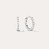The Kiki Crystal Huggie Earrings in Sterling Silver feature a sparkling row of white gemstones. Shown facing forward and from the side, they are versatile everyday essentials for any ear piercing.
