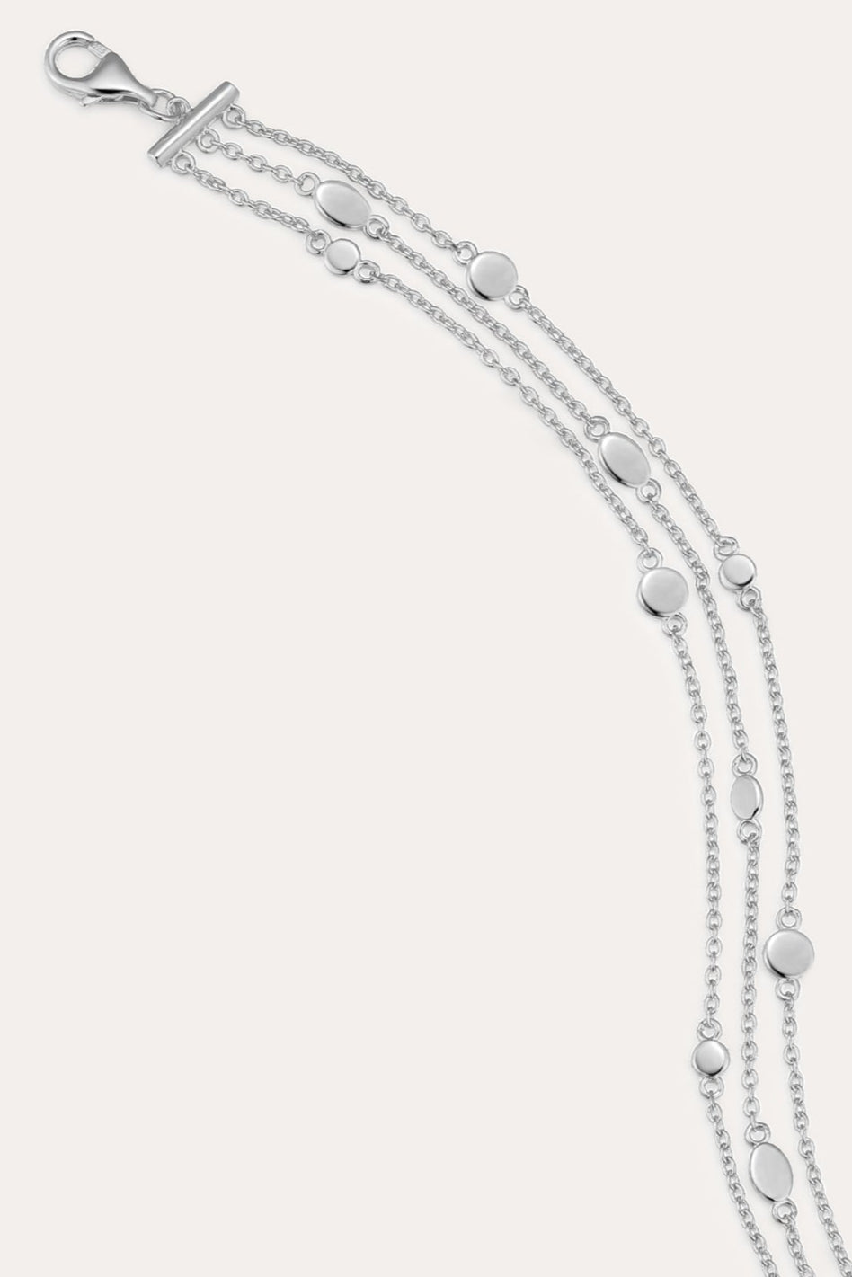 The Simone Triple Chain Layered Bracelet in Silver features three delicate sterling silver chains adorned with small round and oval disc accents, finished with a lobster clasp closure.