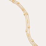 A triple layered gold bracelet with chain links and small circular embellishments, fastened with a lobster clasp.
