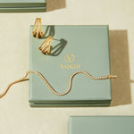A jewelry box featuring a pair of earrings and the Alba Tennis Necklace in Gold.