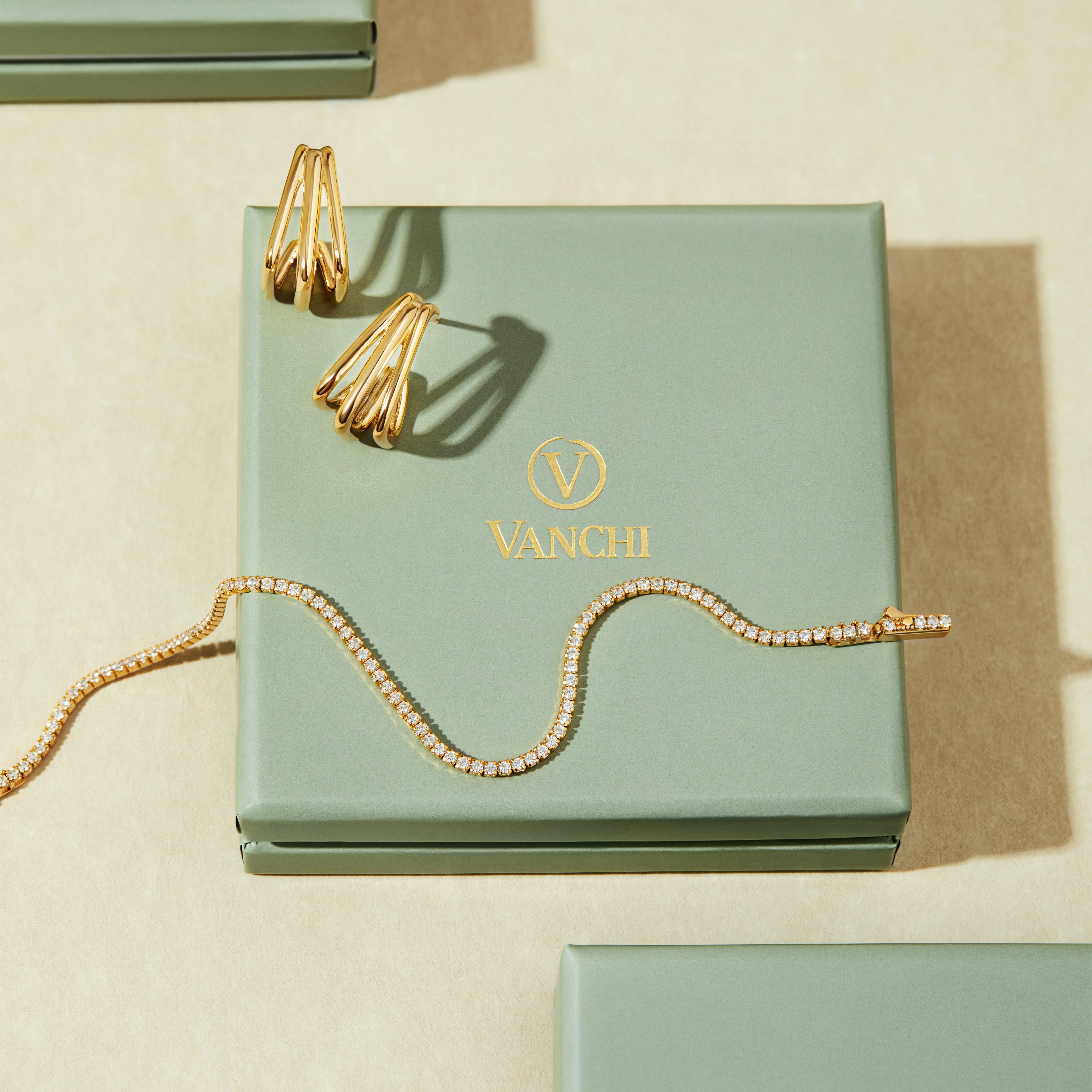 A jewelry box featuring a pair of earrings and the Alba Tennis Necklace in Gold.